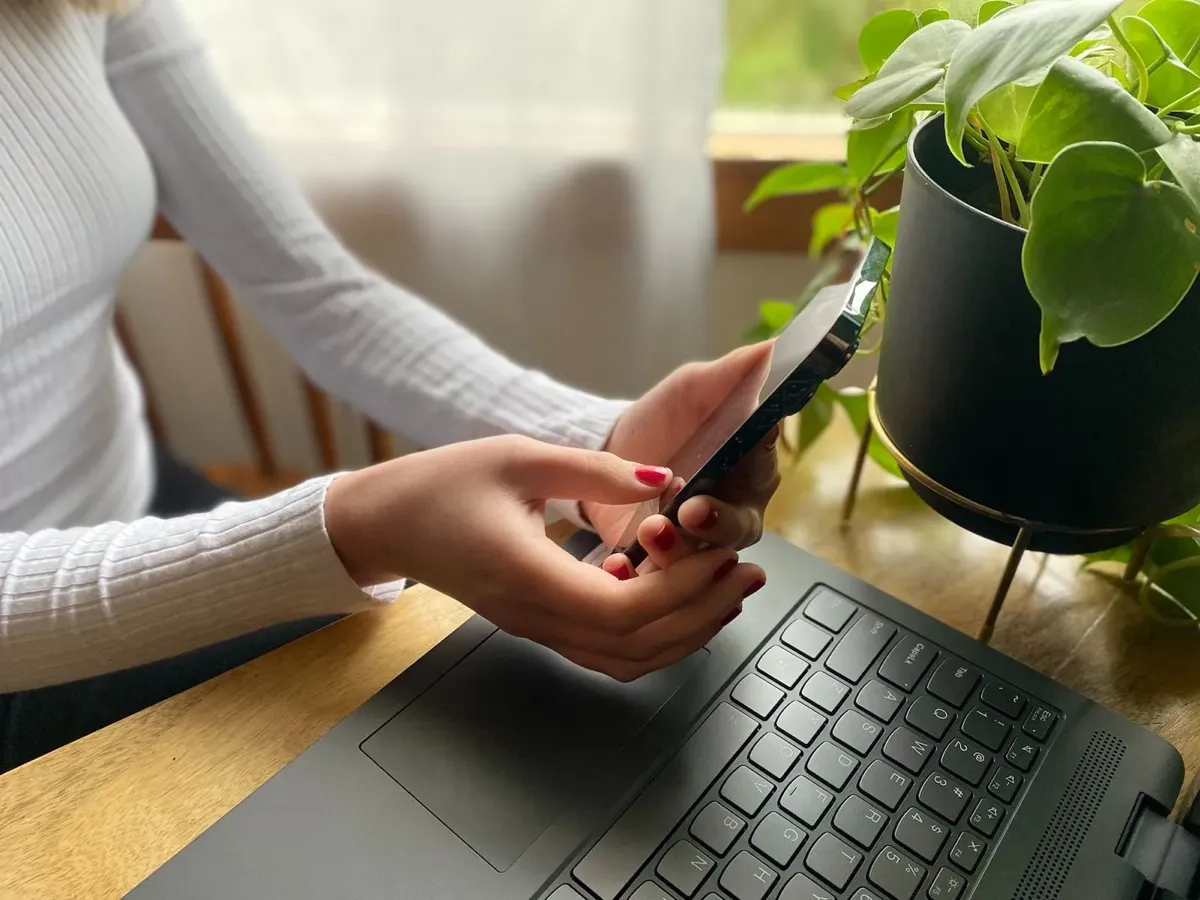 woman holding phone at computer